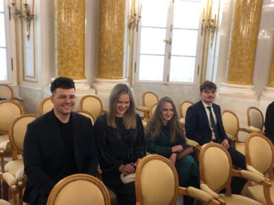 Zdjęcie zrobione w zabytkowej sali na Zamku Królewskim przedstawia czworo studentów nagrodzonych stypendium Ministra