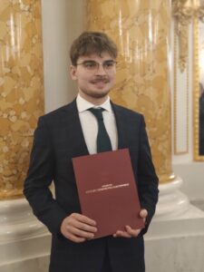 Na zdjęciu uśmiechnięty student Przemysła Sidor w eleganckim garniturze, po wręczeniu stypendium Ministra Kultury