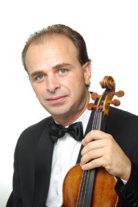 Kolorowy portret zdjęciowy mężczyzny w eleganckim fraku, który trzyma w lewej ręce skrzypce