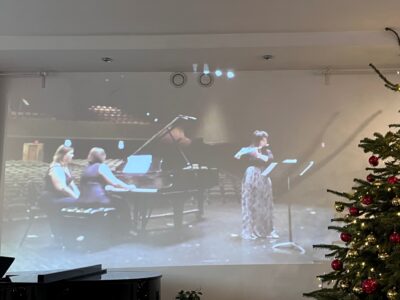 Zdjęcie z koncertu w ramach Kultura 3.0 przedsawia flecistkę i pianistkę na ekranie Studia Gallois