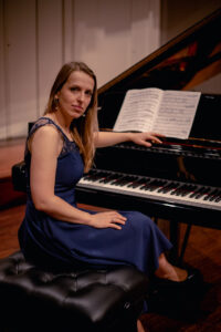 Na zdjęciu kobieta siedząca przy fortepianie - pianistka Hanna Lizinkiewicz