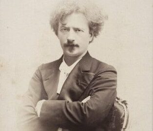 Czarno-białe zdjęcie Ignacego Jana Paderewskiego z założonymi rękami.