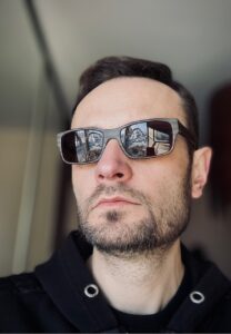 Na zdjęciu Patryk Piłasiewicz - portret w okularach przeciwsłonecznych