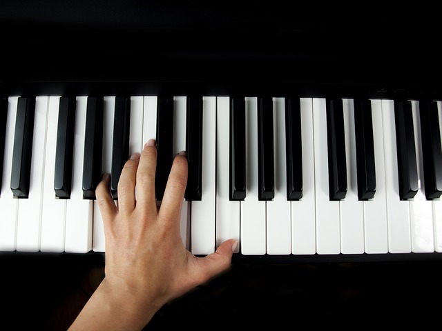 Widać dłoń na klawiaturze fortepianu - zdjęcie może zachęcać do przyjścia na koncert fortepianowy