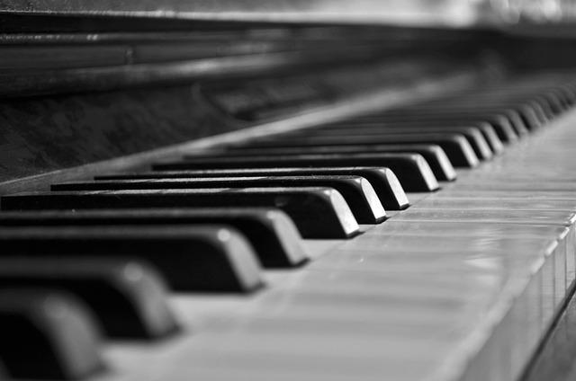 CZarno-białe zdjęcie przedstawia fragment klawiatury fortepianu