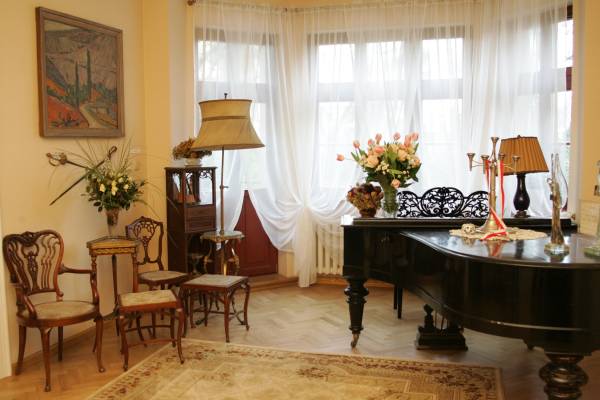 Zdjęcie przedstawia salon muzyczny Feliksa Nowowiejskiego w Willi Wśród Róż i może zachęcać do przyjścia na recital