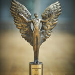 Fotografia przedstawia wykonaną z mosiądzu postać ze skrzydłami - statuetkę Muzyczne Orły